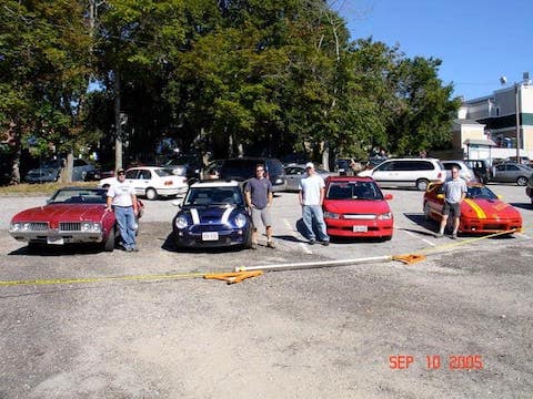 four cards with drivers standing next to the cars.